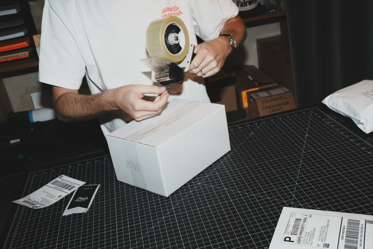 Fairwell Collective team member sealing a shipping box with packing tape