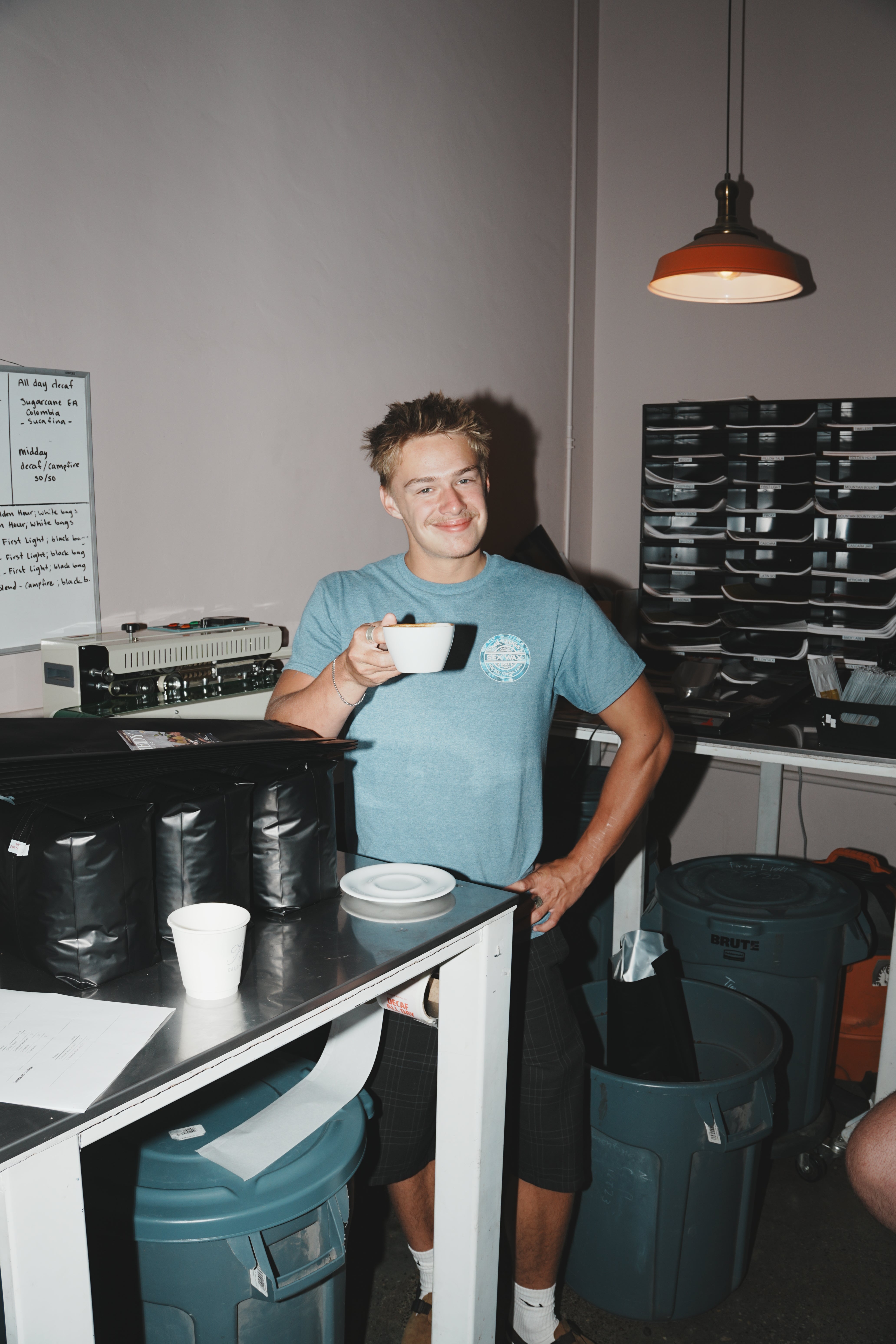 Team member in a branded shirt smiling with a coffee cup