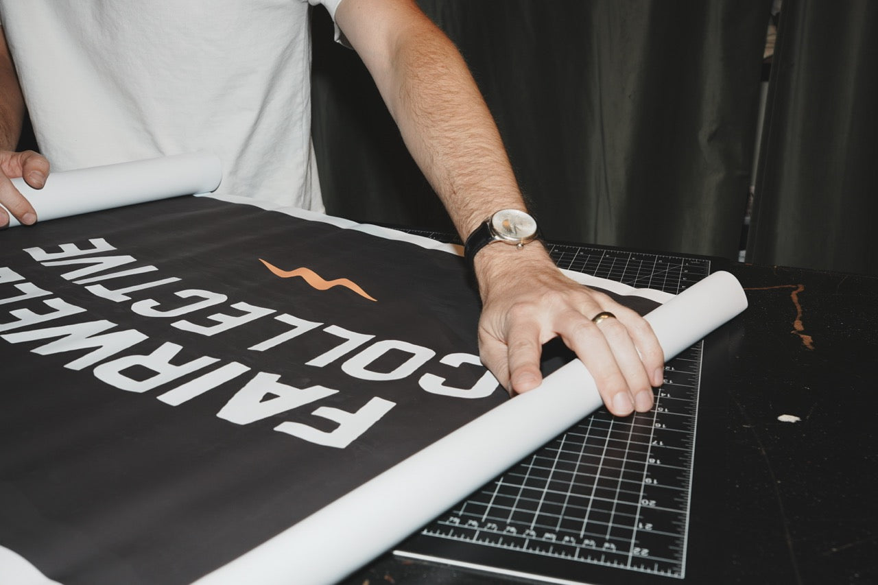 Close-up of a printed Fairwell Collective brand banner with the wave logo mark