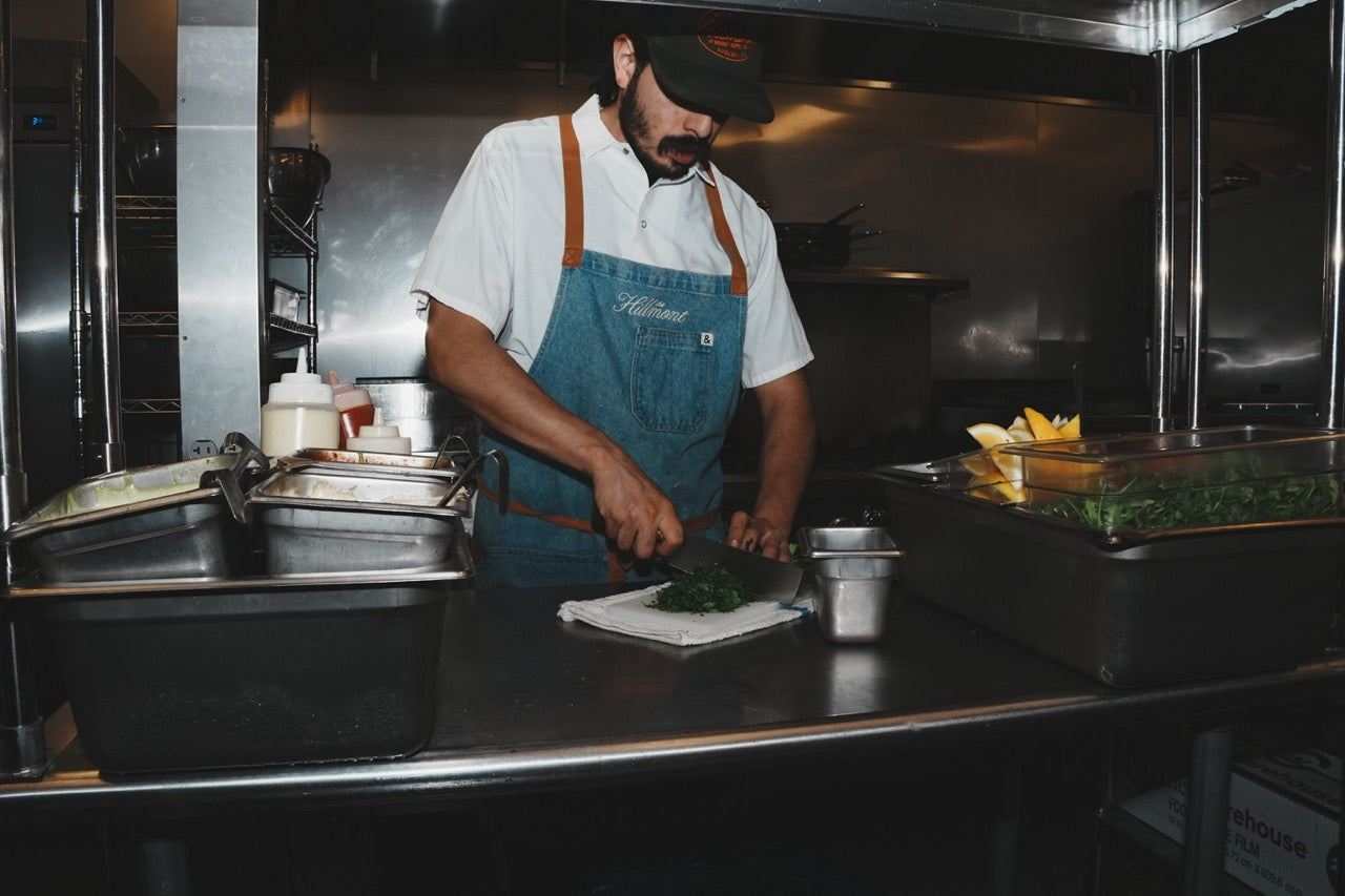 Chef wearing a branded apron and cap in the restaurant kitchen