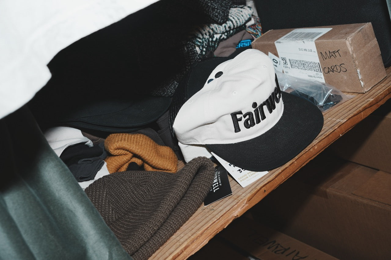 Fairwell Collective branded cap and custom card box on a desk